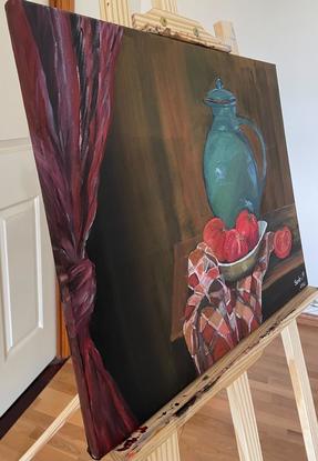 Still life painting of a green jug and a bowl of ripe tomatoes sitting on a tea towel, placed on an old wooden table. The painting tries to capture a rustic background with a knotted drapes hanging by the side.