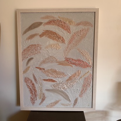 A white textured background with bronze, gold, and other metallic coloured feather floating. A very textured piece. 