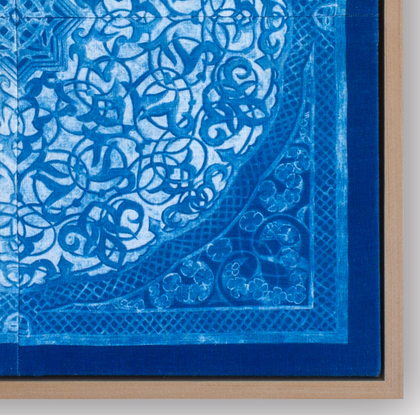 a square image, of a blue biomorphic pattern based on a plaster carving from the Attarine Madrasa in Fez. Inside the square, is a circular emblem that is filled with arabesque pattern detail. it is framed inside a natural wood float-frame