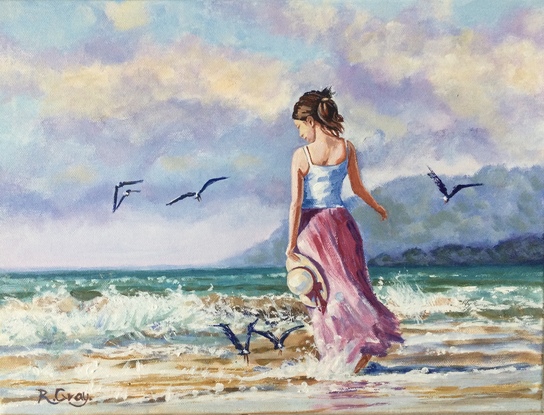 Woman in long dress walking on beach with seagulls flying nearby 