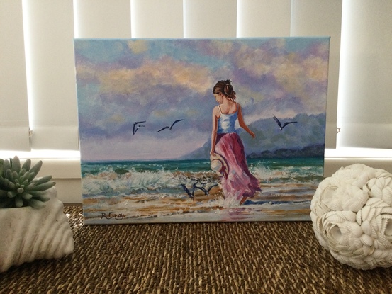 Woman in long dress walking on beach with seagulls flying nearby 