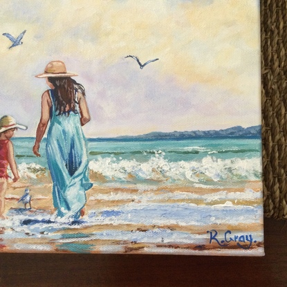 Woman and child on beach with seagulls, cloudy sky