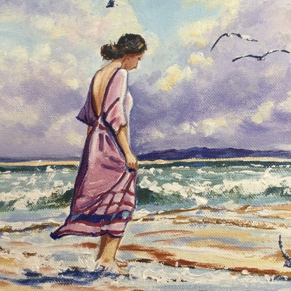 Woman walks on beach at sunset, seagulls in sky.