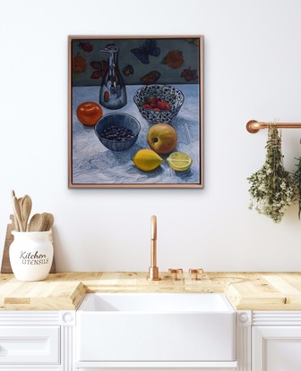 Bowls of berries, an apple, lemons, mandarin and silver oil jug on white tablecloth 
