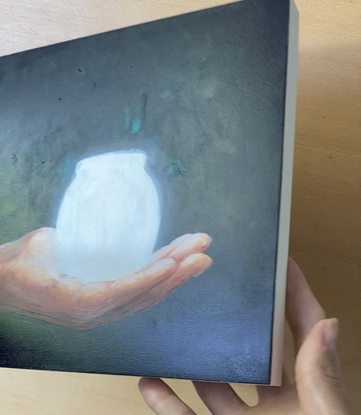 Youth's hand holding a glowing jar against a dark background.