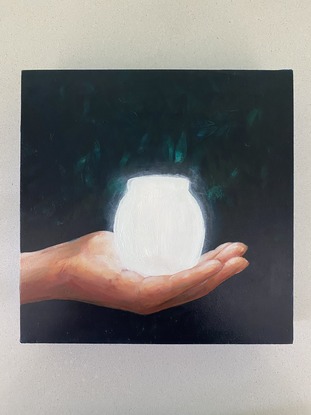 Youth's hand holding a glowing jar against a dark background.