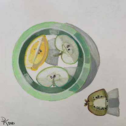 Apple segments and a lemon wedge arranged on a plate at the centre of the composition.  A quarter of a kiwi in the bottom right hand corner on a white background.