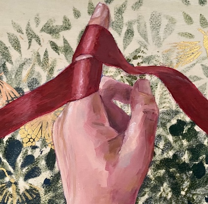 A woman's hand holding a red ribbon against a background of green foliage.