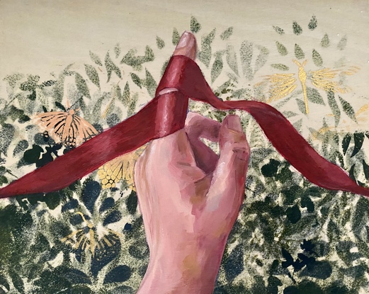 A woman's hand holding a red ribbon against a background of green foliage.