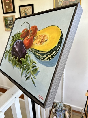 An aubergine,  three tomatoes and a section of pumpkin lying on a bed of basil leaves