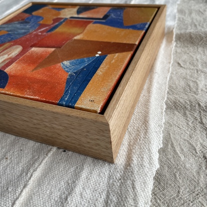 Square canvas board with paper collage in orange and blue blocks of colour in abstract shapes. 