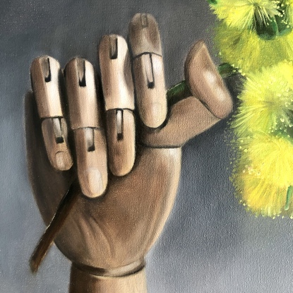 Artist wooden hand holding an Illyarrie red cap gum blossom.