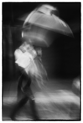 Fighting the Wind. 
"I didn’t invent the rainy day, I just own the best umbrella." From the ‘Ordinary Interesting - Street Streak’ body of work. A single shot in-camera by emerging artist Ann Parrott with a Limited Edition of 21. Brisbane city.