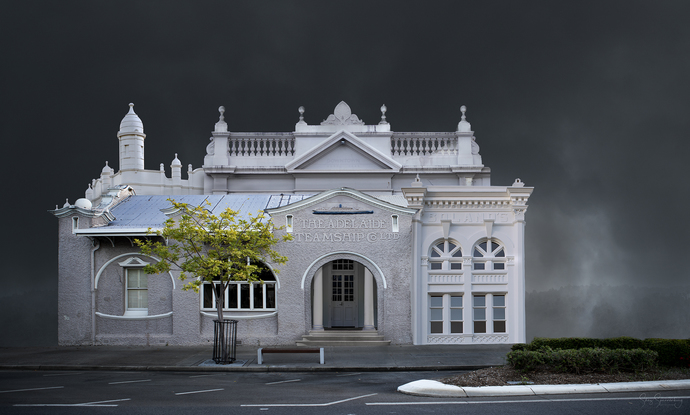 A combination of greyish white heritage style architecture appearing almost ghost like out of a dark steamy stormy background.