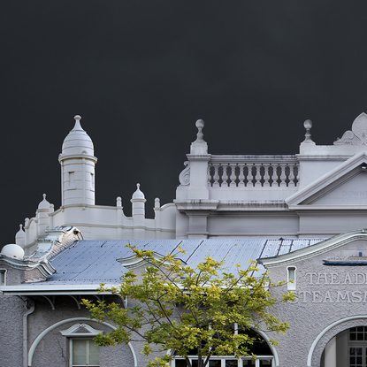 A combination of greyish white heritage style architecture appearing almost ghost like out of a dark steamy stormy background.