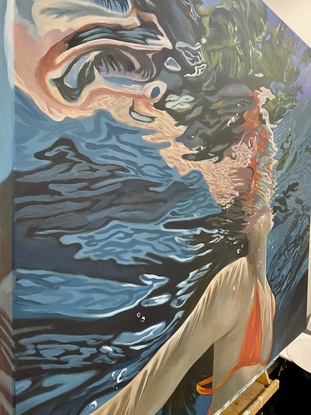 View of woman underwater wearing orange bikini with reflections and landscape distortions.