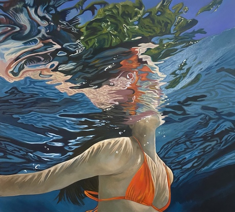 View of woman underwater wearing orange bikini with reflections and landscape distortions.