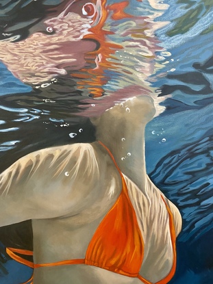 View of woman underwater wearing orange bikini with reflections and landscape distortions.