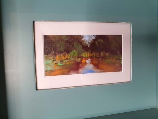 Small abstract impressionist oil painting of lagoon with reflections of Australian bush and blue sky. Green and blue with ochre highlights. Teal shadow box frame. 