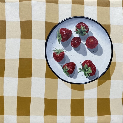 A yellow and white checked linen table cloth with a White and black plate on it with whole fresh strawberries scattered on that plate.