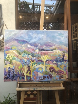 An Australian landscape painting inspired by the Flinders Ranges.  The style is impressionistic and fanciful.  It’s a colourful painting, with lots of yellow, pink, purple, ochre, green. Red and blue.