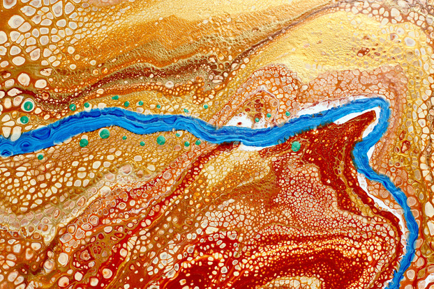 outback ochre and golds with a bright blue river running through with spots of green representing trees along a river after rainy season