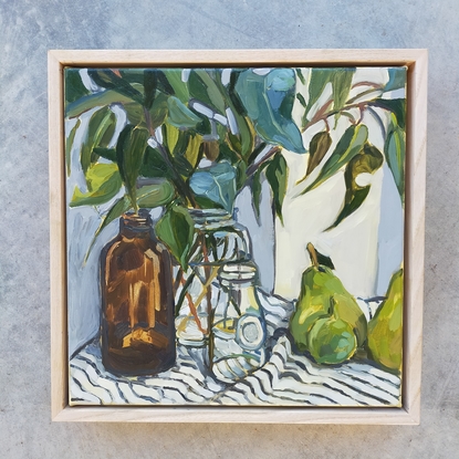  gum leaves in glass bottles and green fruit on a striped tablecloth 