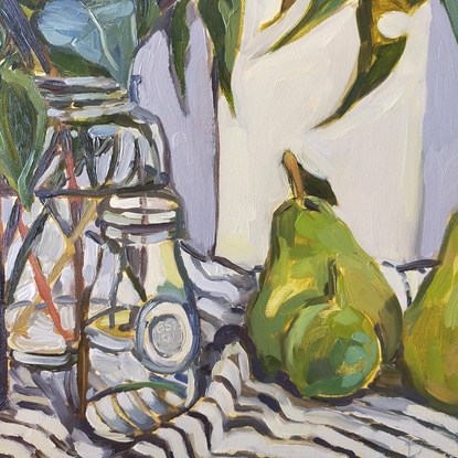  gum leaves in glass bottles and green fruit on a striped tablecloth 