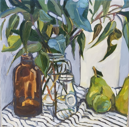  gum leaves in glass bottles and green fruit on a striped tablecloth 