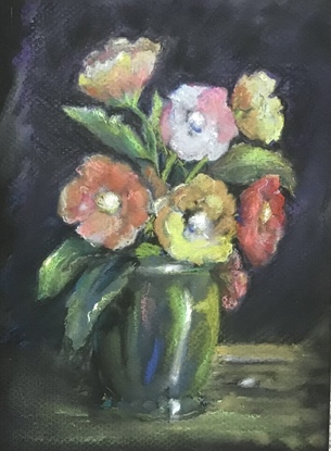 A softly arranged bunch of six flowers, possibly roses, with white centres. They are in a green shiny vase possibly a glazed pottery vase. Colours of the flowers are red, pink yellow and a soft orange colour with some leaves in the lower section


