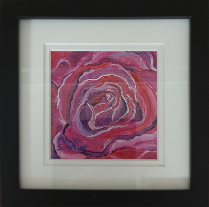 a macro look at the swirling petals of a crimson and red rose in bloom in miniature