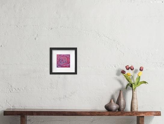 a macro look at the swirling petals of a crimson and red rose in bloom in miniature