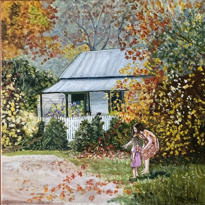 Woman and child looking at autumn leaves in front of a cottage