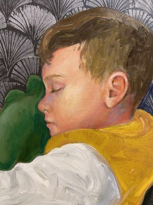 A boy curled up sleeping on his side. He is holding  stuffed dinosaur.