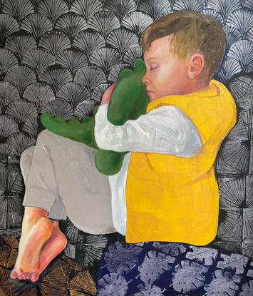 A boy curled up sleeping on his side. He is holding  stuffed dinosaur.