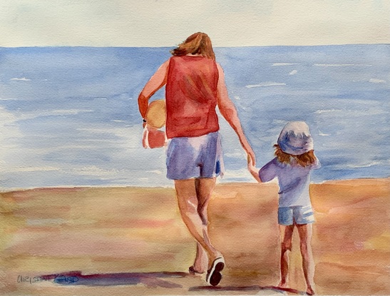 Mother and child walking along a beach in the sunshine.