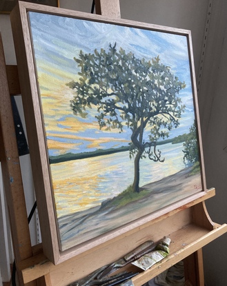 A tree stands on the edge of a lake as the light diminishes at days end.