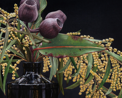 Still life of black, Hendrick’s Gin bottle filled with golden wattle and gumnut bunches on a black background. Warm-coloured, angular rock and one dried leaf perched in front of the bottle. Framed in Japan black stained frame.