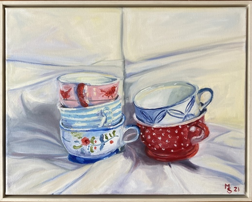 Two stacks of 3 colourfully designed teacups on white drapery