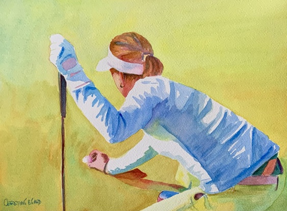 Female golfer lines up her ball on a putting green.