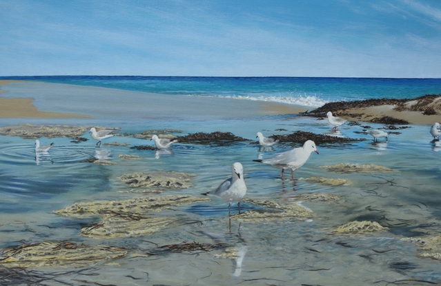 A flock of seagulls rest at the wet sand beach in the sunny day