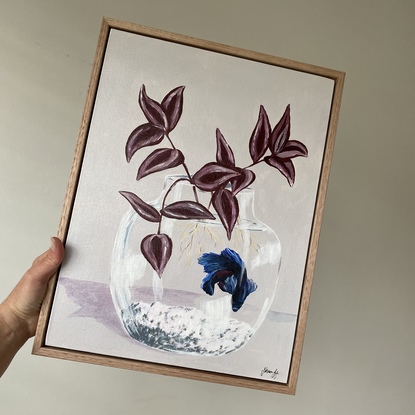 Blue fish swimming in a glass fish tank with maroon leaves growing. 