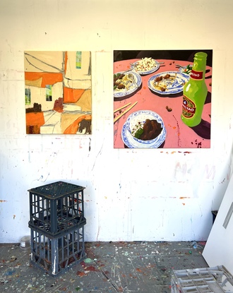 Still life of food and drink at a Chinese restaurant with pink tablecloth and bright green beer bottle