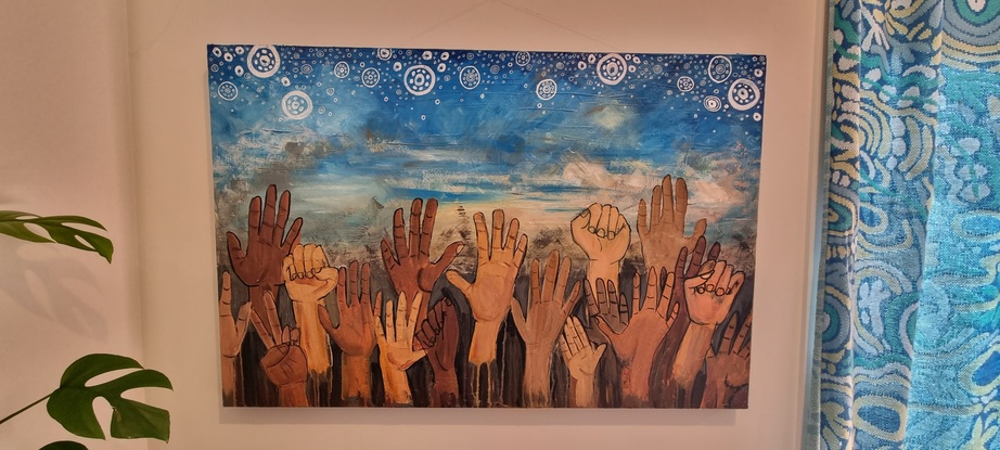 Crowd of hands raised in protest in front of a blue sky with Aboriginal symbols for stars above