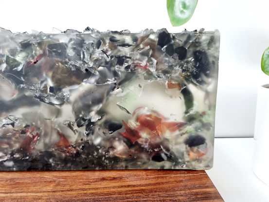 Recycled blown red, black, green and clear glass imbedded in bio resin with a sharp rough top showing  the texture of the glass.