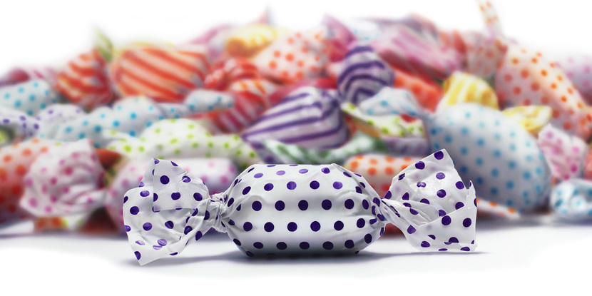 A 2m by 1m painting on canvas of a pile of candy/lolloes in colourful wrappers painted blurred to put attention to one purple polka dotted candy.
The candies are created in hyper realism style -- sharp and in focus. The candies are  a 1,000 times their actual size! .