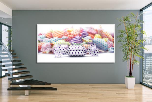 A 2m by 1m painting on canvas of a pile of candy/lolloes in colourful wrappers painted blurred to put attention to one purple polka dotted candy.
The candies are created in hyper realism style -- sharp and in focus. The candies are  a 1,000 times their actual size! .