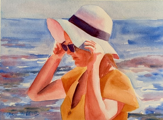 Woman holds her hat in the sunshine.