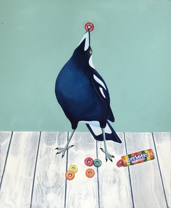 A magpie holding up a Lifesaver confectionery. A roll of Lifesavers and some loose lifesavers lay on the table in front.