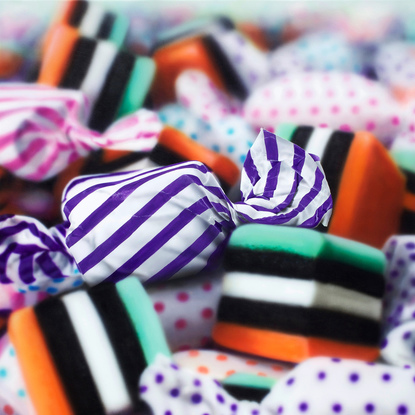 An orange and purple stripped  candy in a pile of multi coloured candies enlarges 1000 times real size. Dynamic photorealism artistry at its finest as it looks so real and pops off the wall

When one views closely, you can see how blur and rougher brush strokes come together for the illusion of realism.